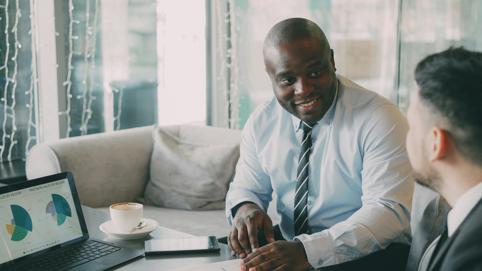 Two business professionals discussing sales charts next to a laptop